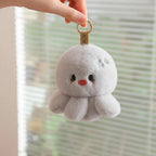 wllio.com light grey plush octopus keychain with embroidered face and dangling legs, attached to a gold ring.