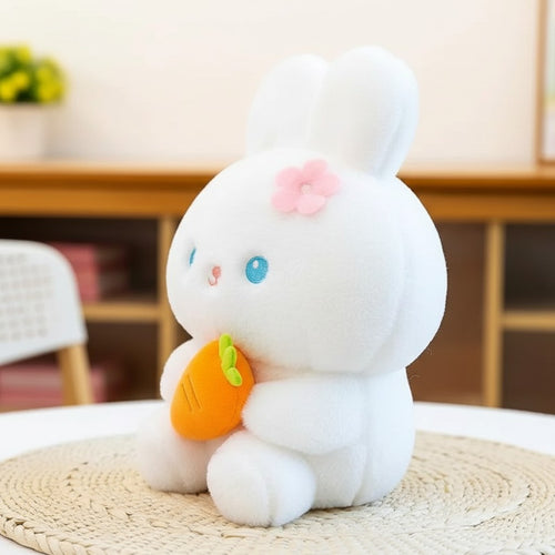 White plush bunny toy with blue eyes, pink flower, and orange carrot accessory by wllio.com